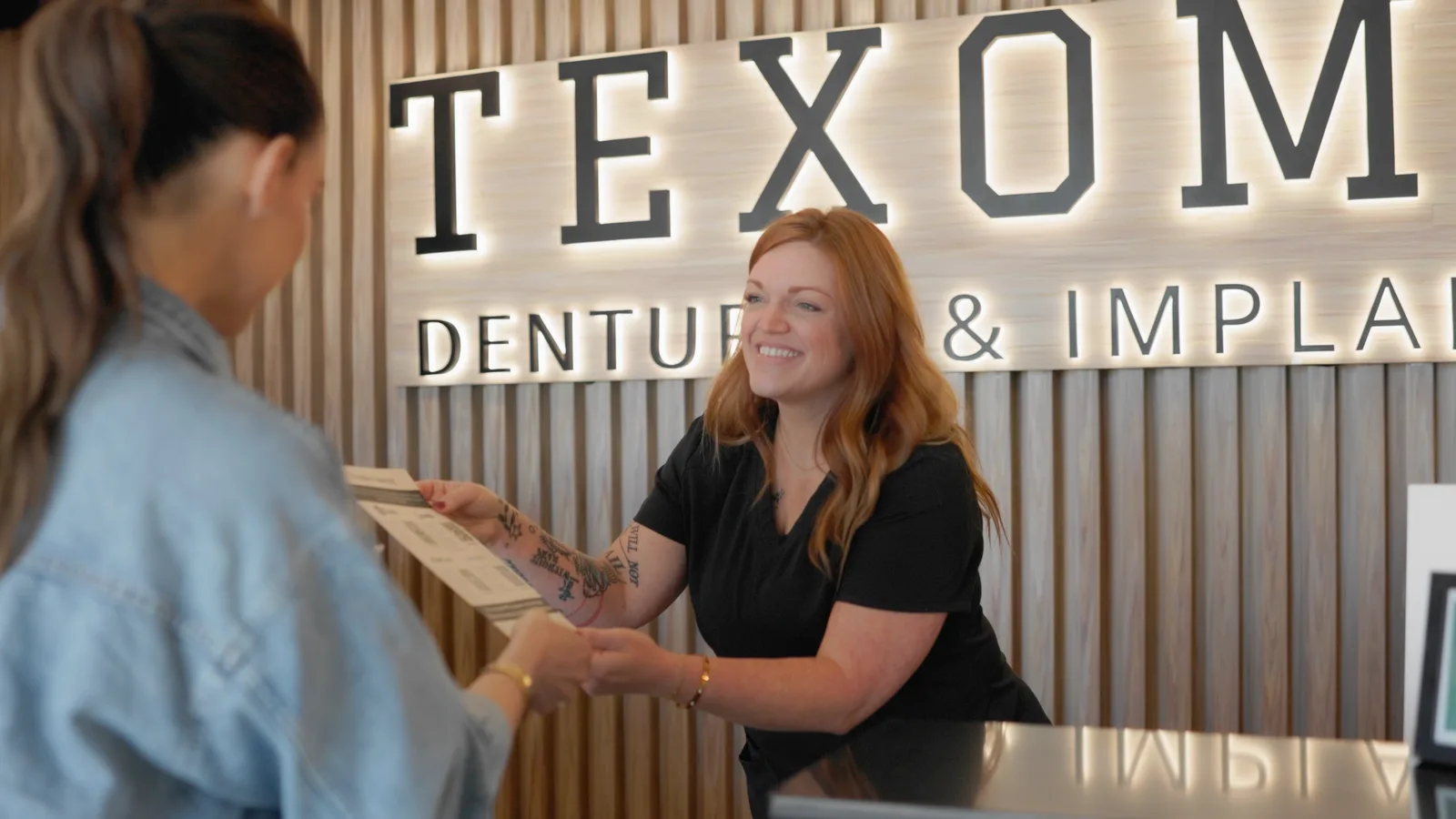 A Texoma Dentures & Implants team member welcoming a patient at the front desk