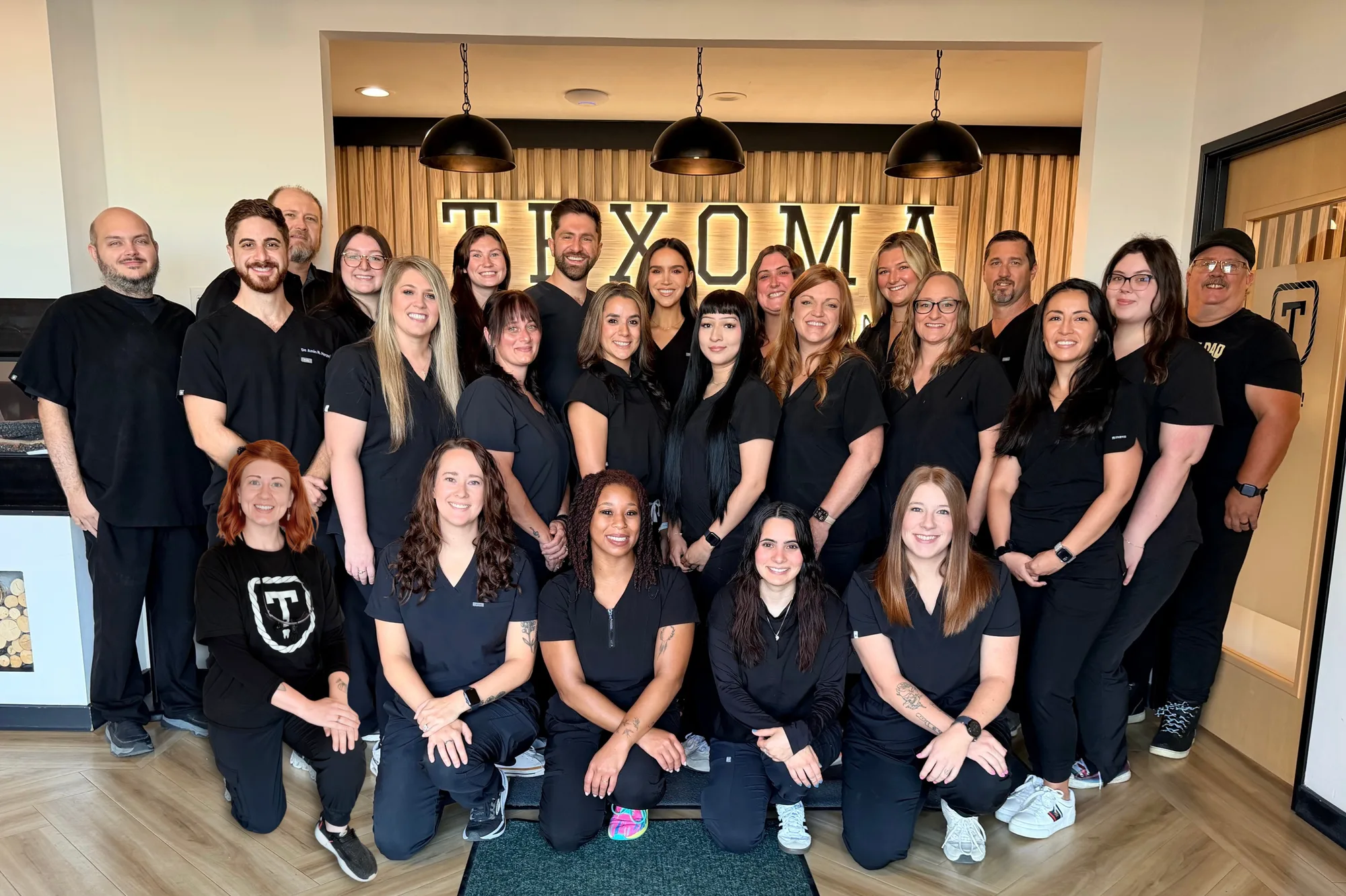 The full Texoma Dentures & Implants team gathered in front of the Texoma sign